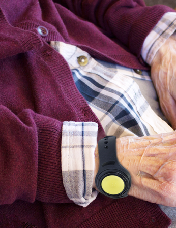 A resident wearing a wristband with a round alarm button on their wrist