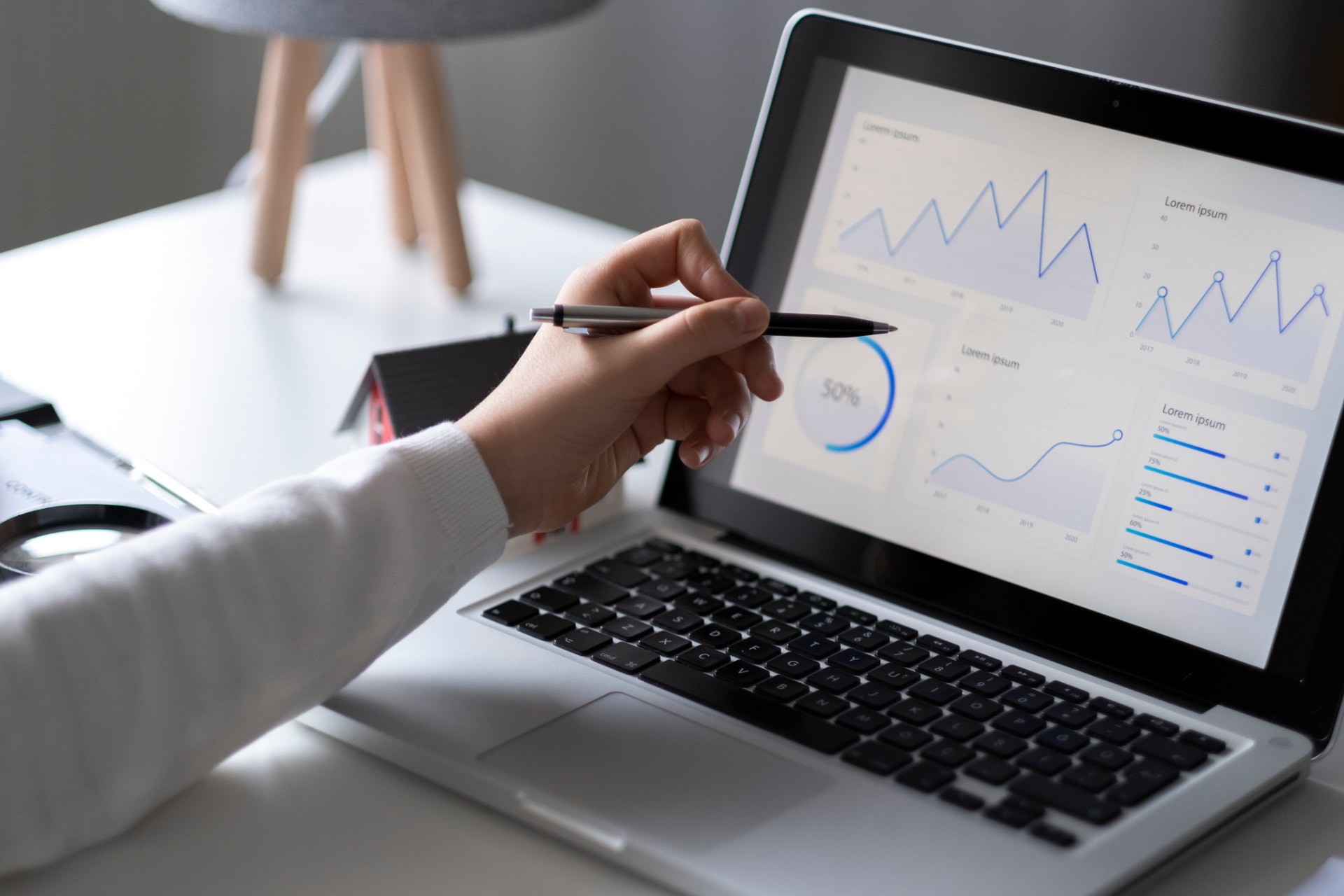 Hand pointing at charts on a laptop screen